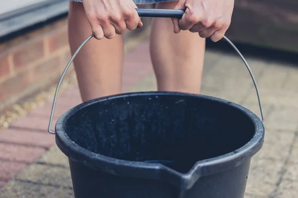 Person hält schwarzen Eimer